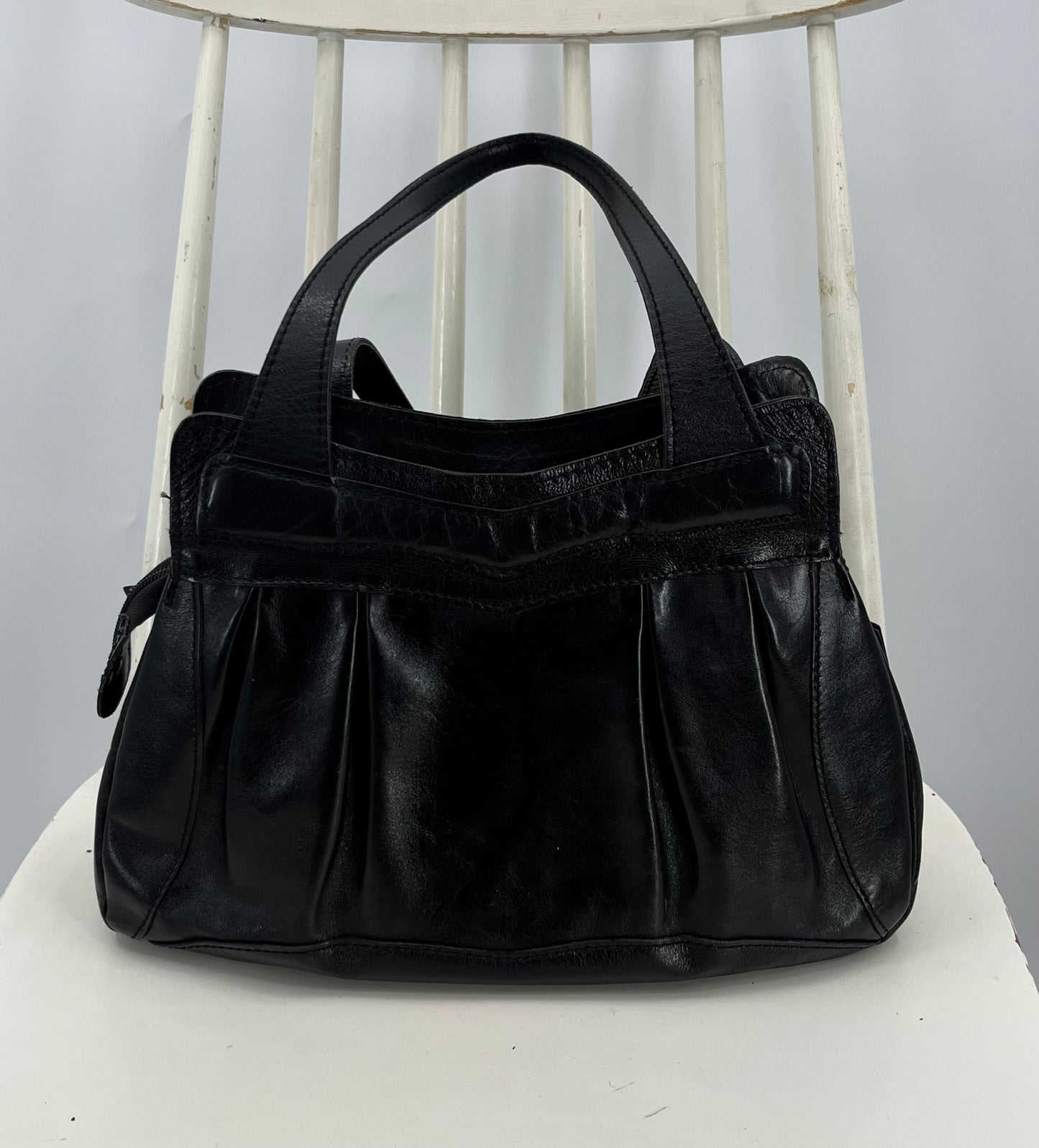 Musta pussukkamallinen käsilaukku, 80-luku