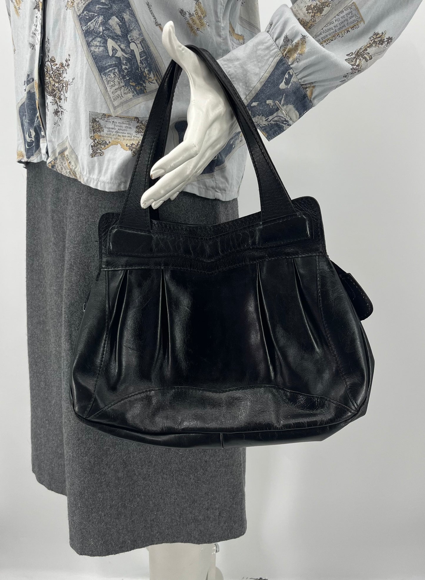 Musta pussukkamallinen käsilaukku, 80-luku