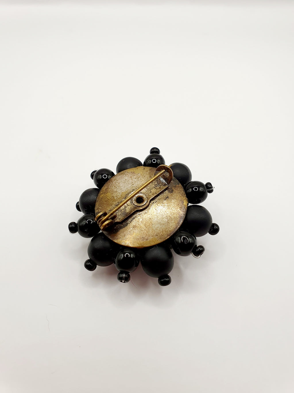 Musta helmistä valmistettu rintakoru, vintage rintakoru, vintage brooch, kuva taustasta