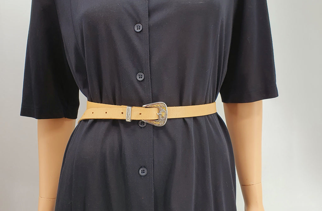 Kapea nahkavyö 1980-luvulta, väri beige, koristeelliset metalliosat, vyö mallinuken päällä