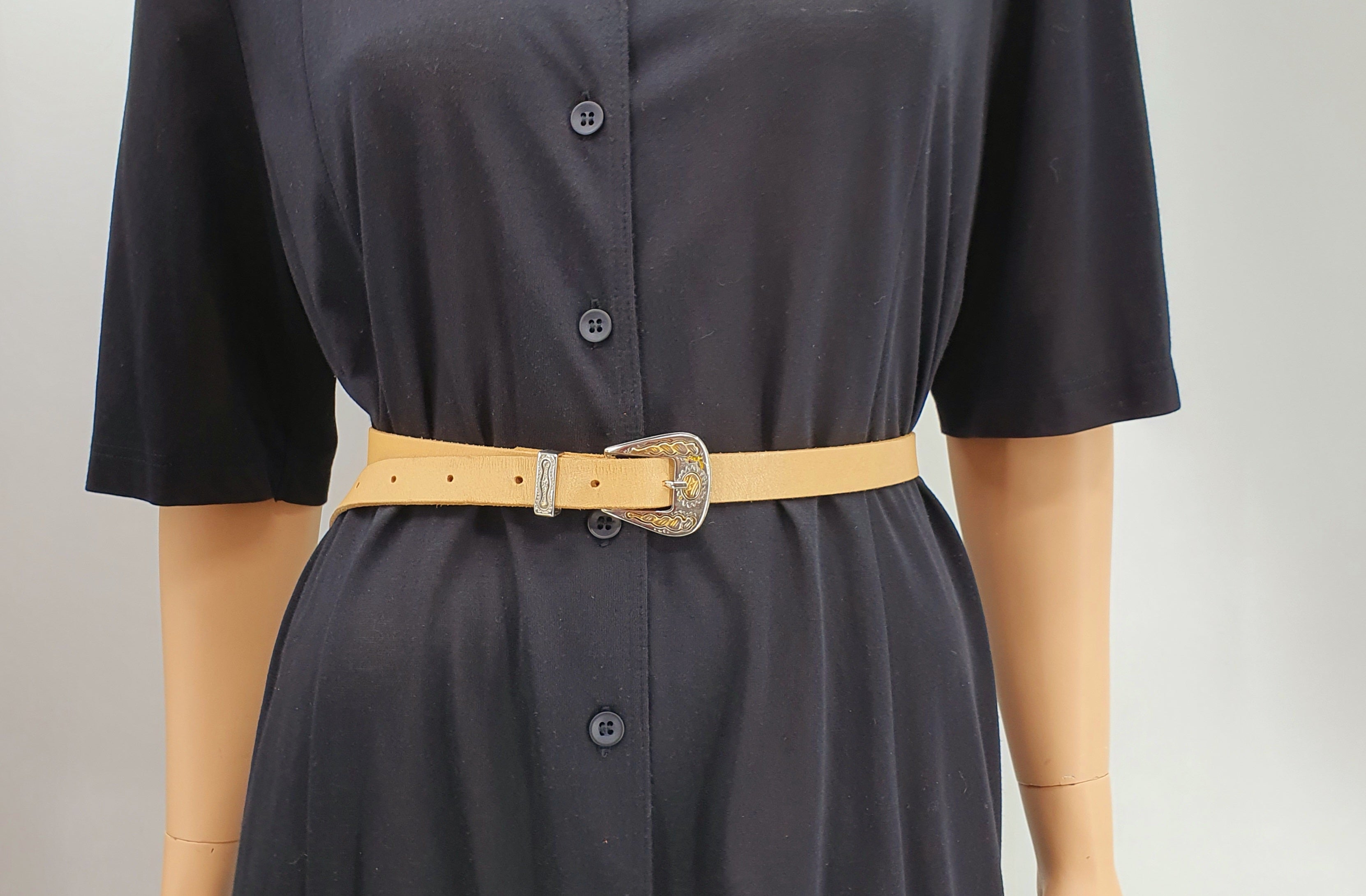 Kapea nahkavyö 1980-luvulta, väri beige, koristeelliset metalliosat, vyö mallinuken päällä