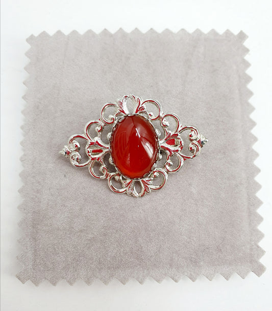 Brooch, brick red pearl on a lace-like background