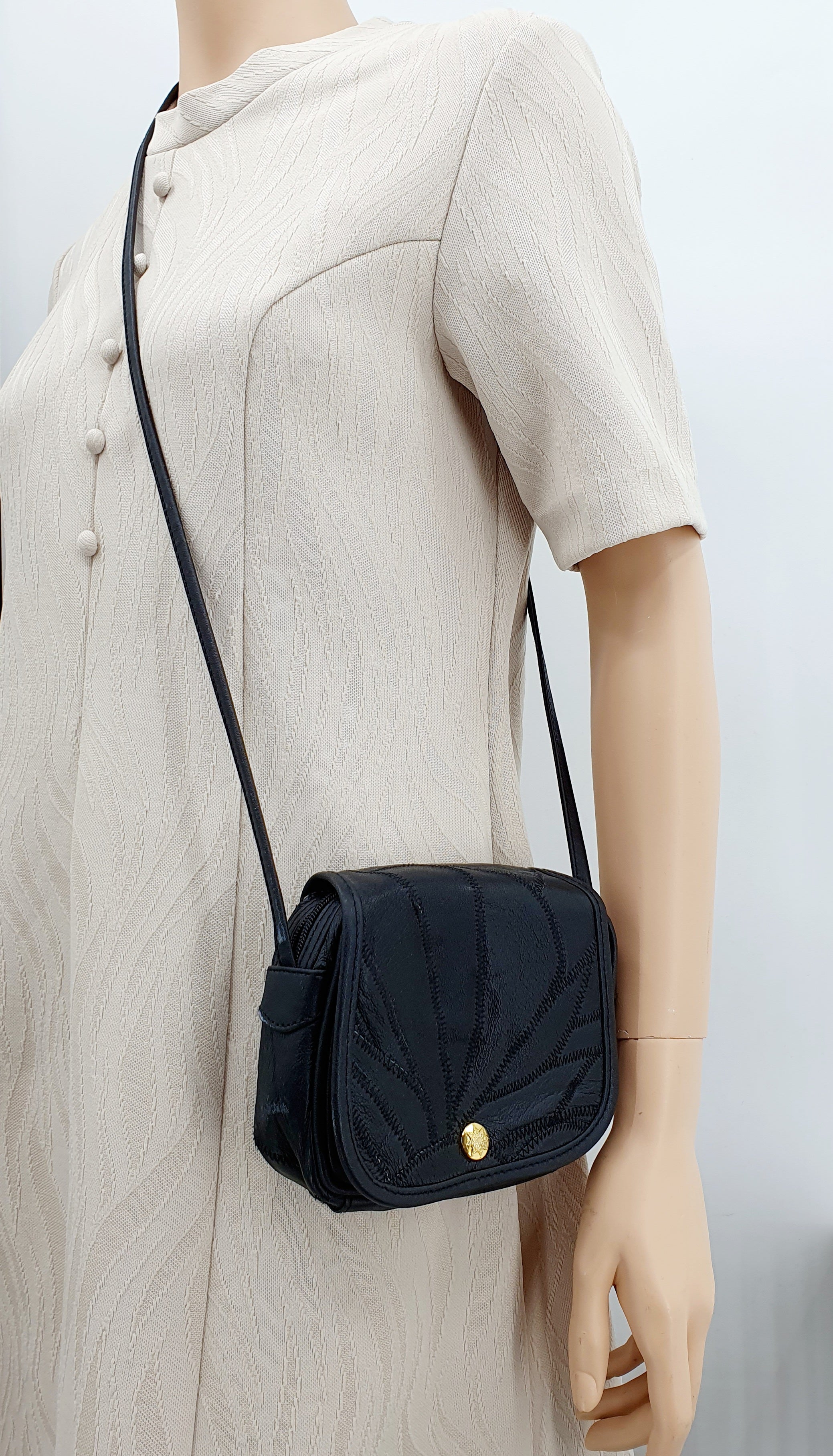 Musta nahkapalakuvioinen olkalaukku 90-luvulta, kuva mallinuken päällä