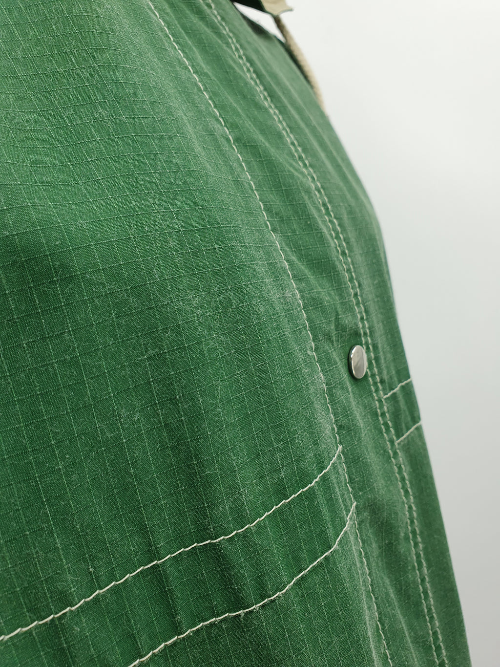 Kosteuttapitävä välikausitakki 90-luvulta, väri vihreä-luunvalkoinen, kuva kankaan pinnasta