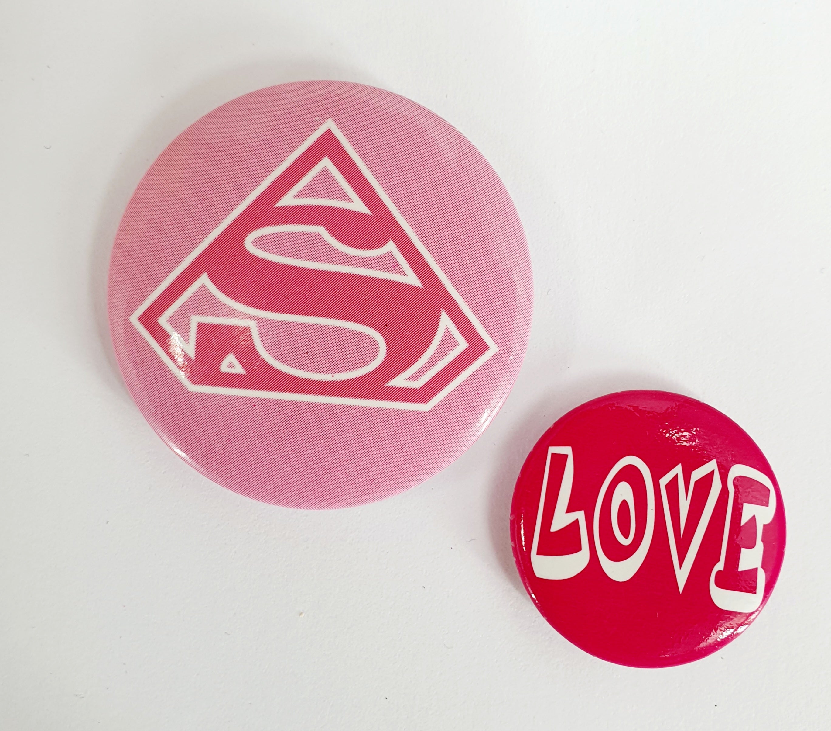 Two badges, "Supergirl" and "Love"
