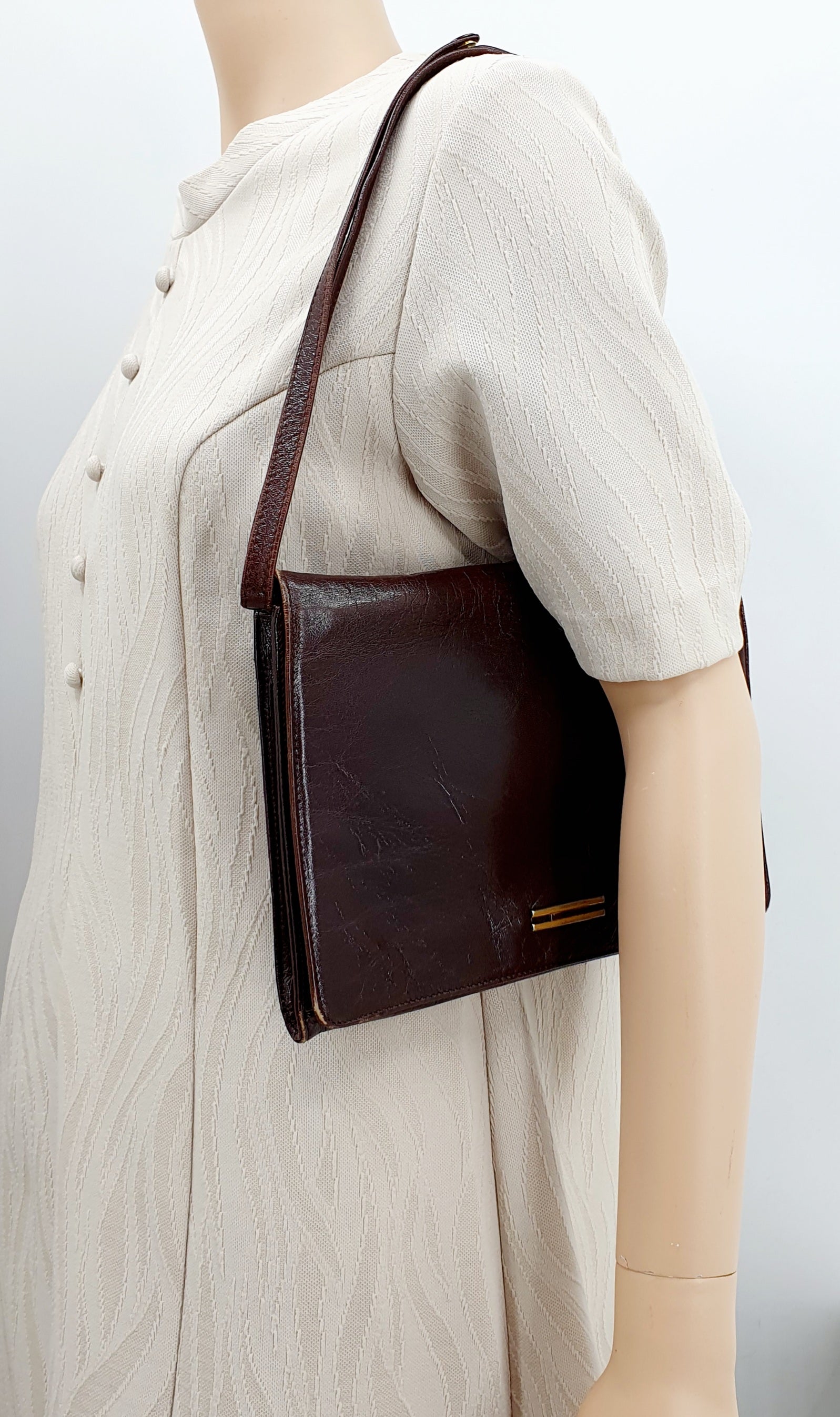 Tummanruskea vintage olkalaukku 1970-luvulta, kuva laukusta mallinuken olalla