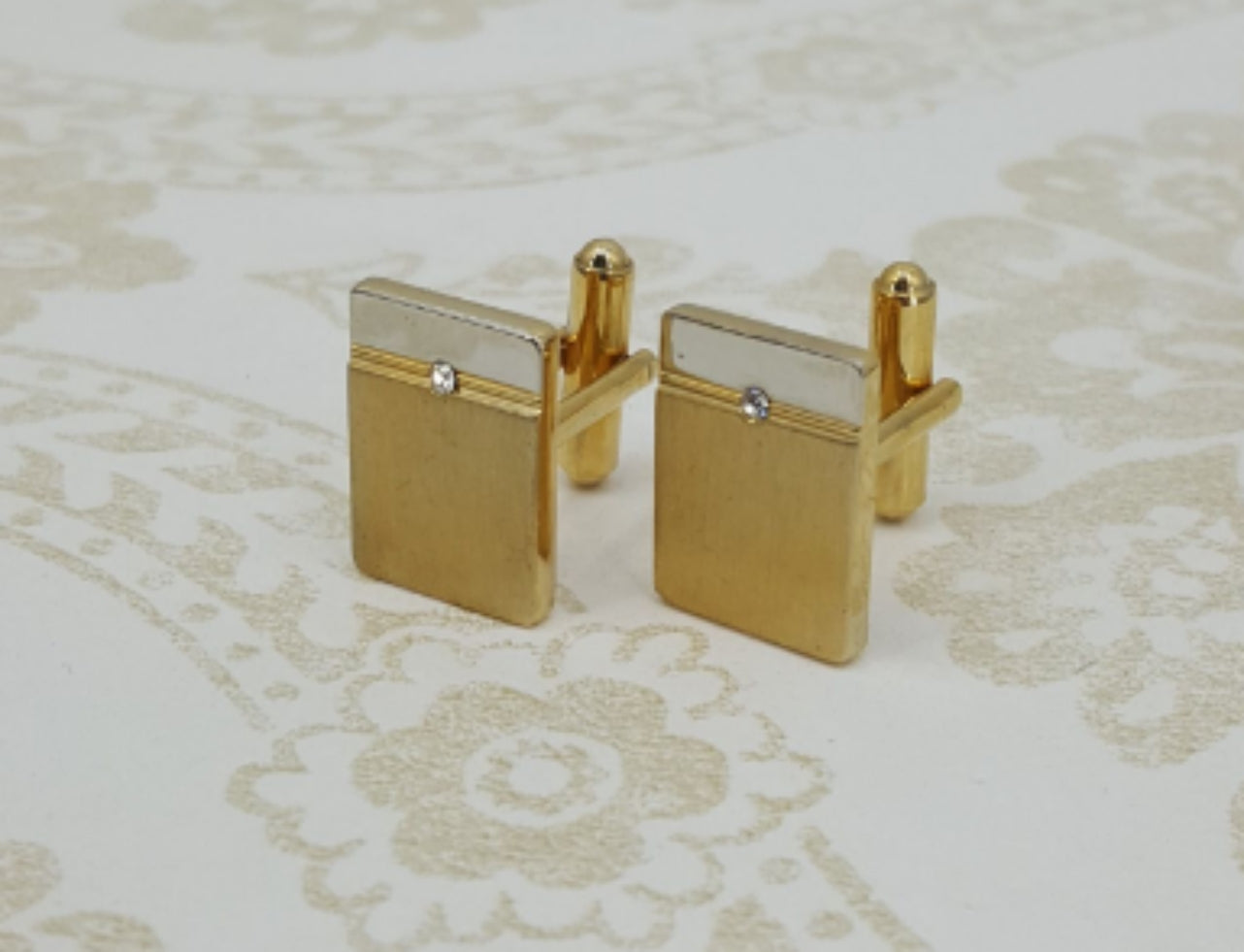 Gold-colored cufflinks with a small rhinestone
