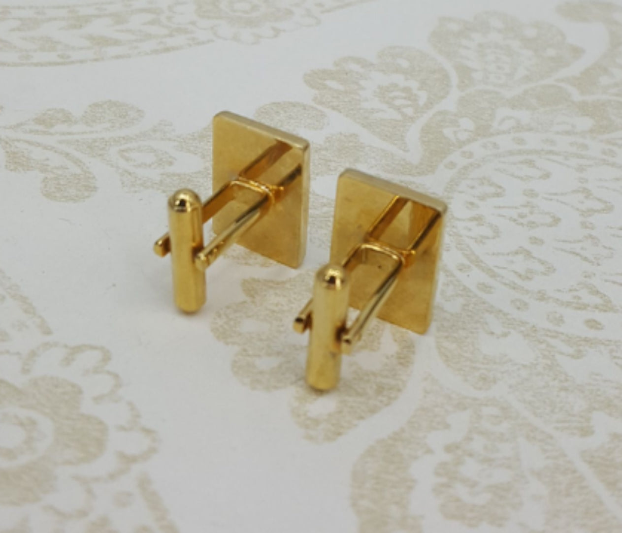 Gold-colored cufflinks with a small rhinestone